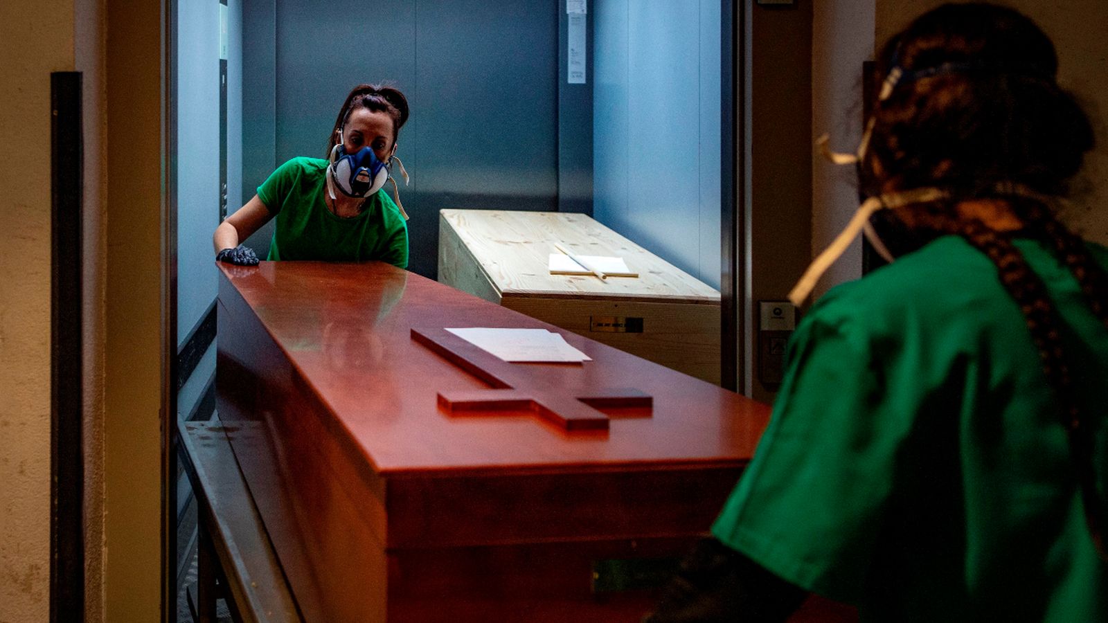 Dues treballadores d'una funerària traslladen el taüt d'una víctima del coronavirus