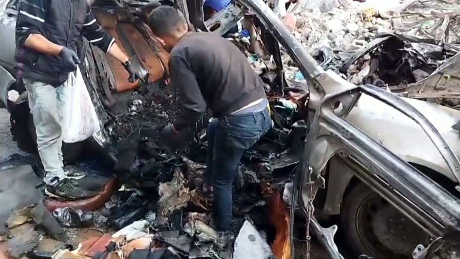 Un home escarba entre les restes del vehicle on viatjaven tres fills i tres nets del líder polític de Hamàs, morts per l'impacte d'un míssil israelià