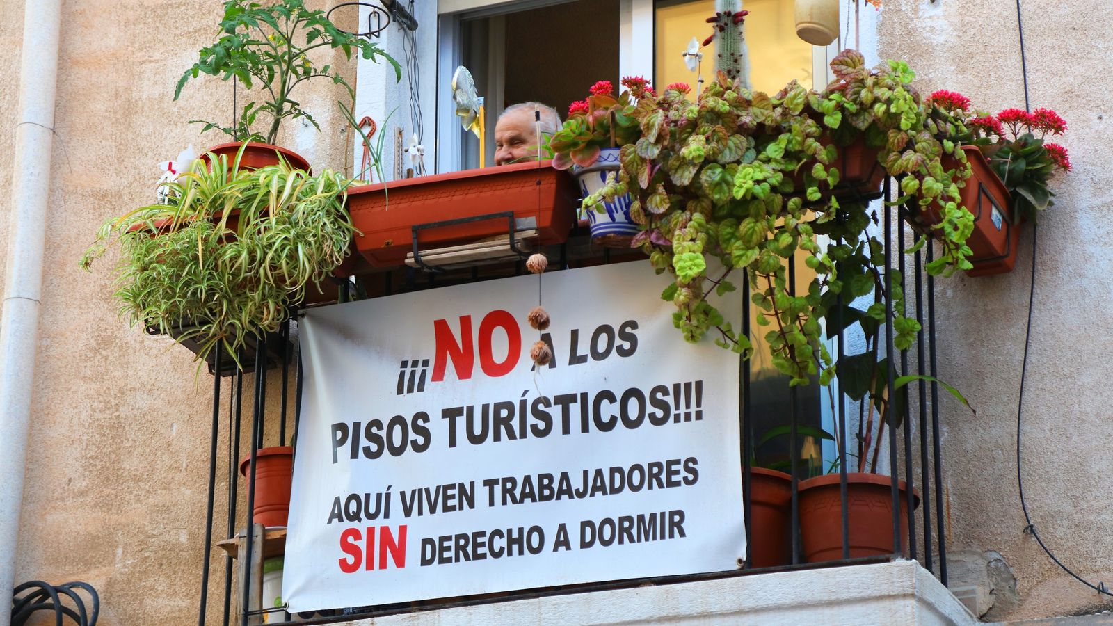 Un veí penja un cartell contra els pisos turístics al balcó de sa casa