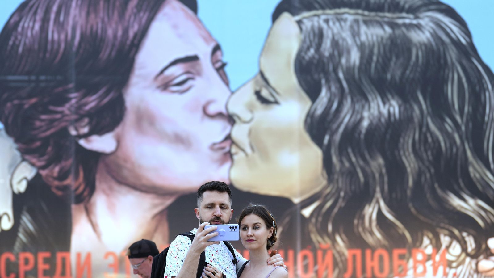 Una parella es fa una foto davant la lona del bes de Colau i Ayuso del Primavera Sound de Barcelona