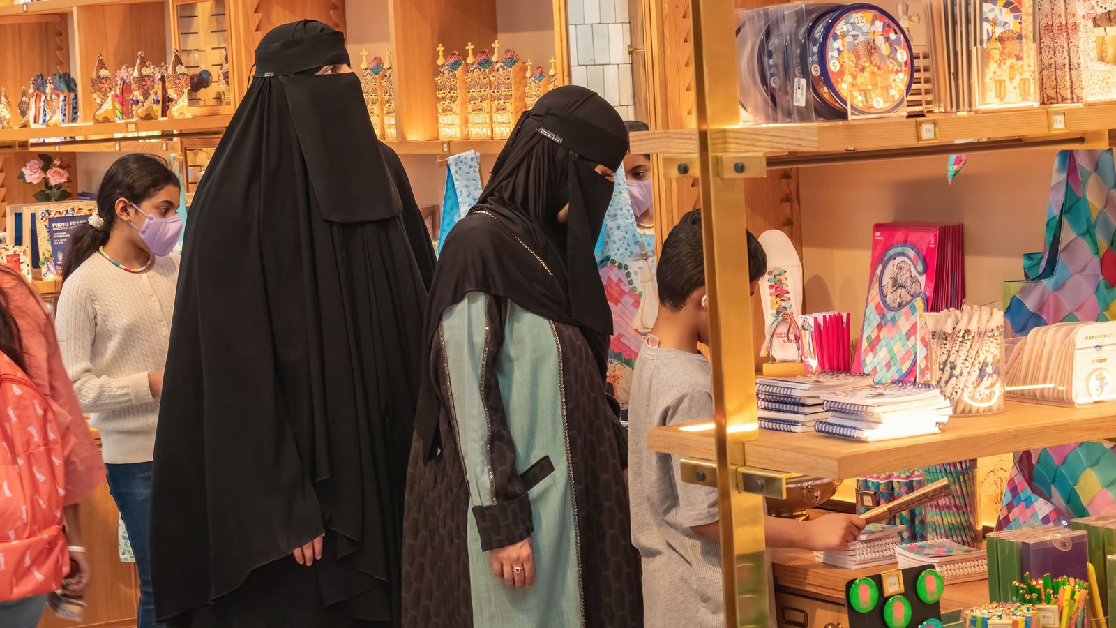 Dos dones amb el rostre cobert observen les prestatgeries d'una botiga de Barcelona