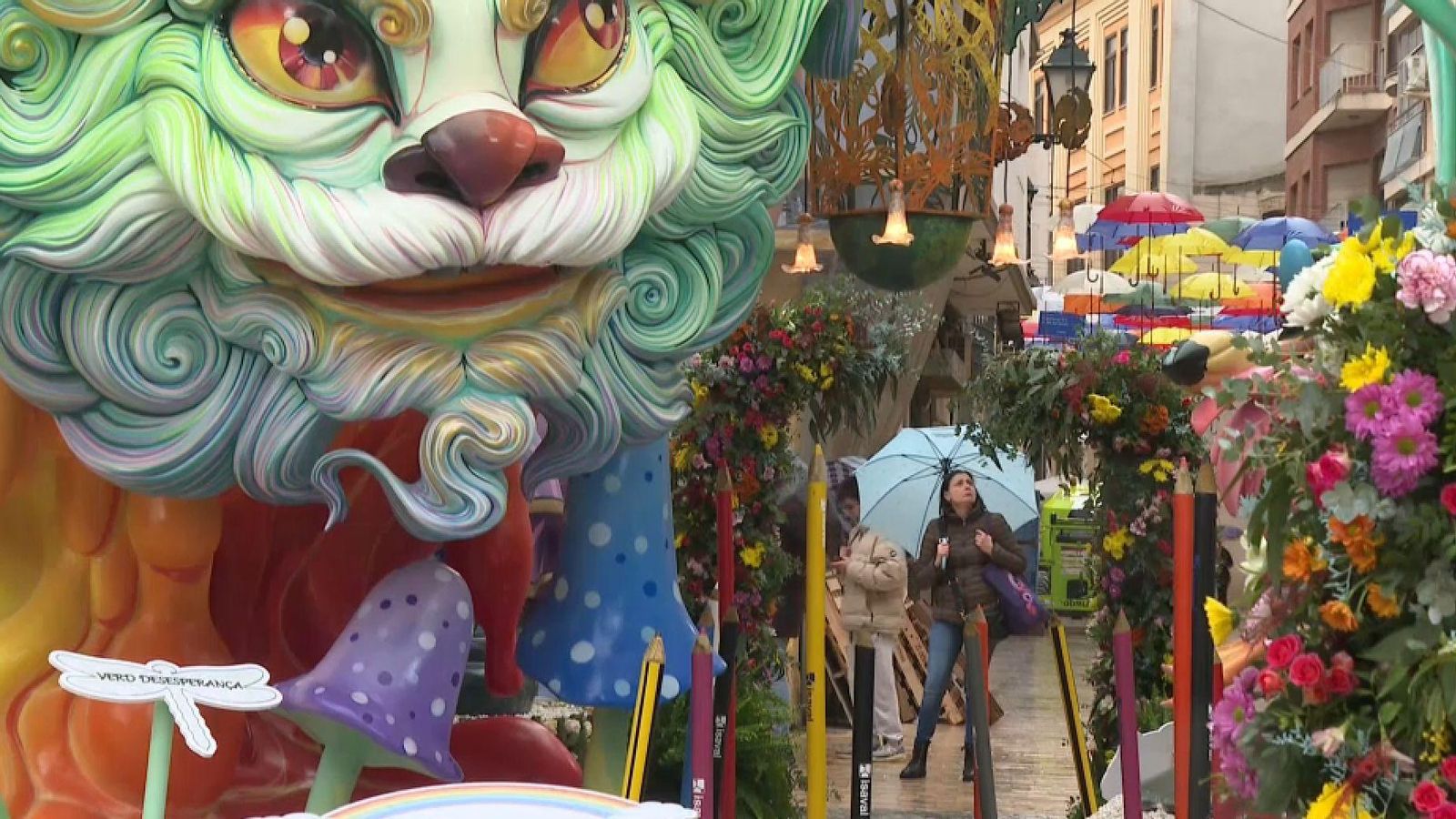 Una vianant observa una falla d'Alzira amb un paraigua per a resguardar-se de la pluja