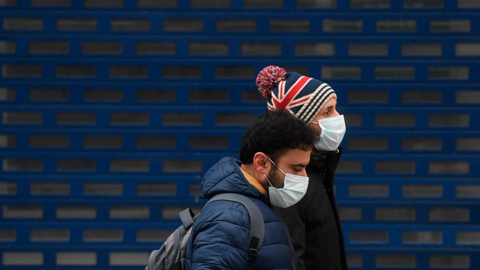 Dues persones amb mascareta passen per una botiga tancada a Oxford Street, inusualment tranquil·la a Londres