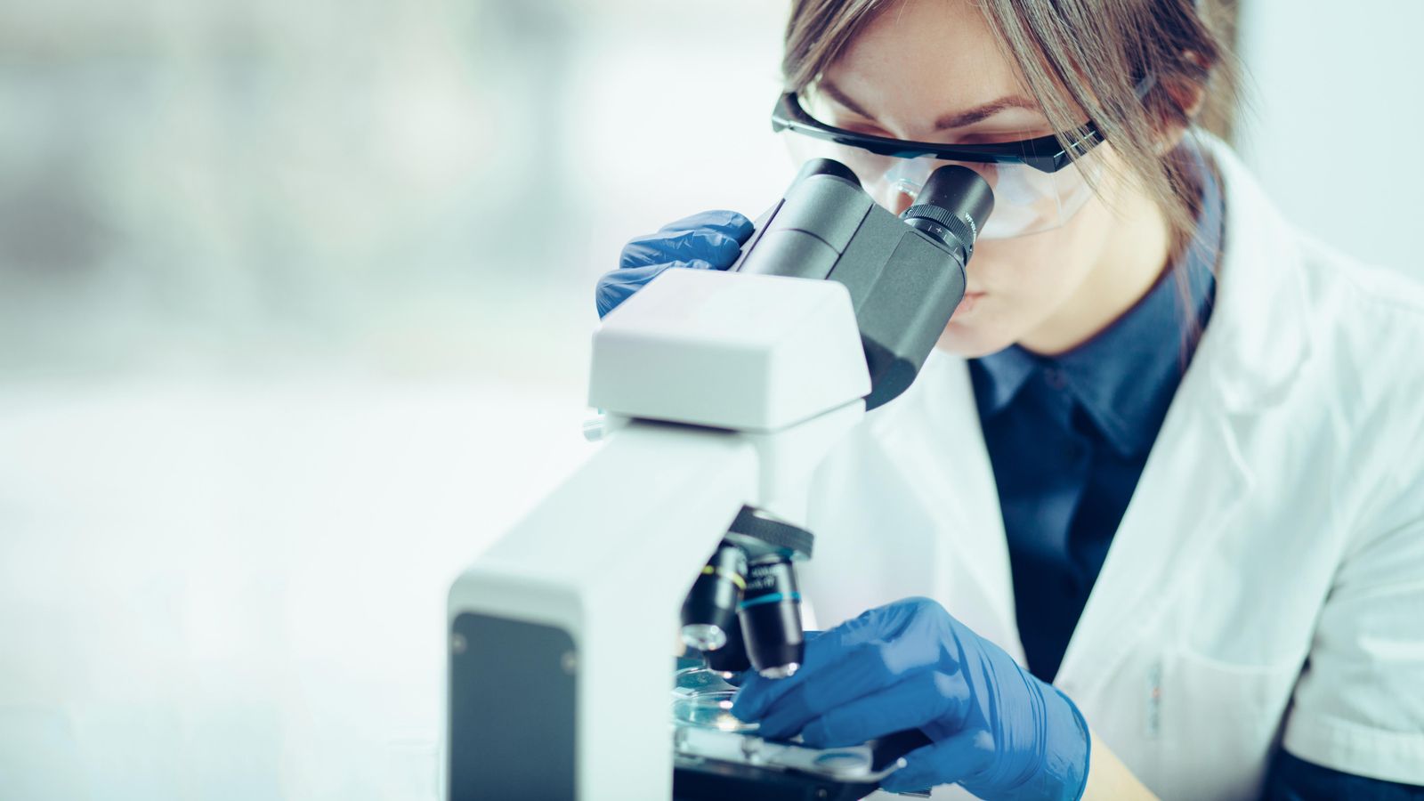 Una jove investigadora mira per un microscopi