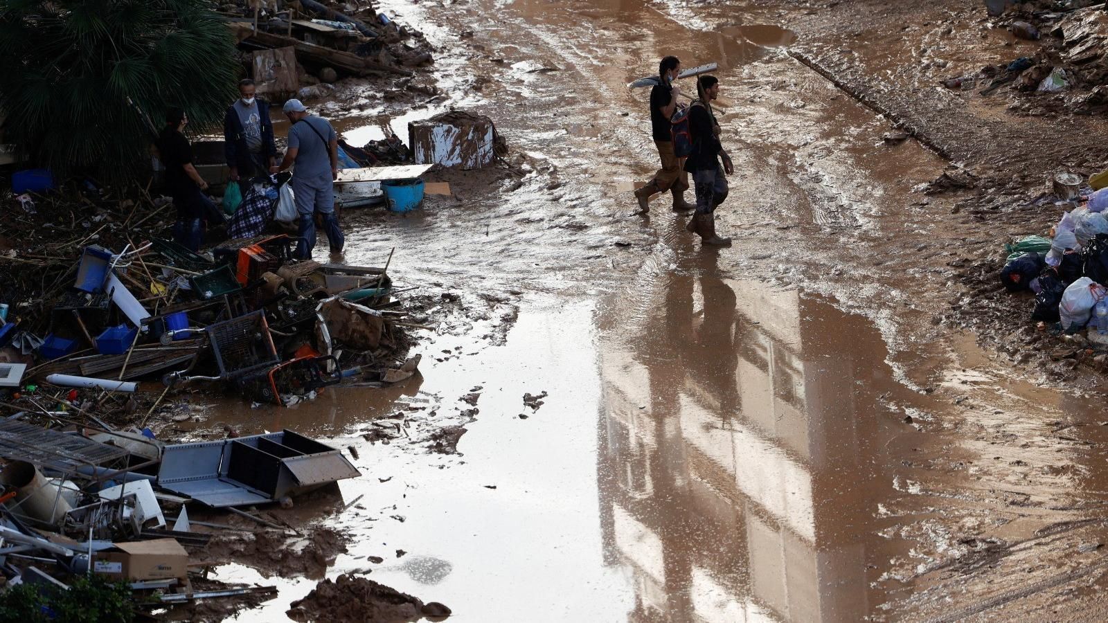Diverses persones caminen per un carrer de Paiporta ple de fang
