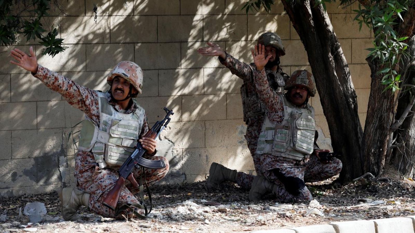 Soldats paramilitars refugiats darrere d'un mur durant l'atac al consolat xinés al Pakistan