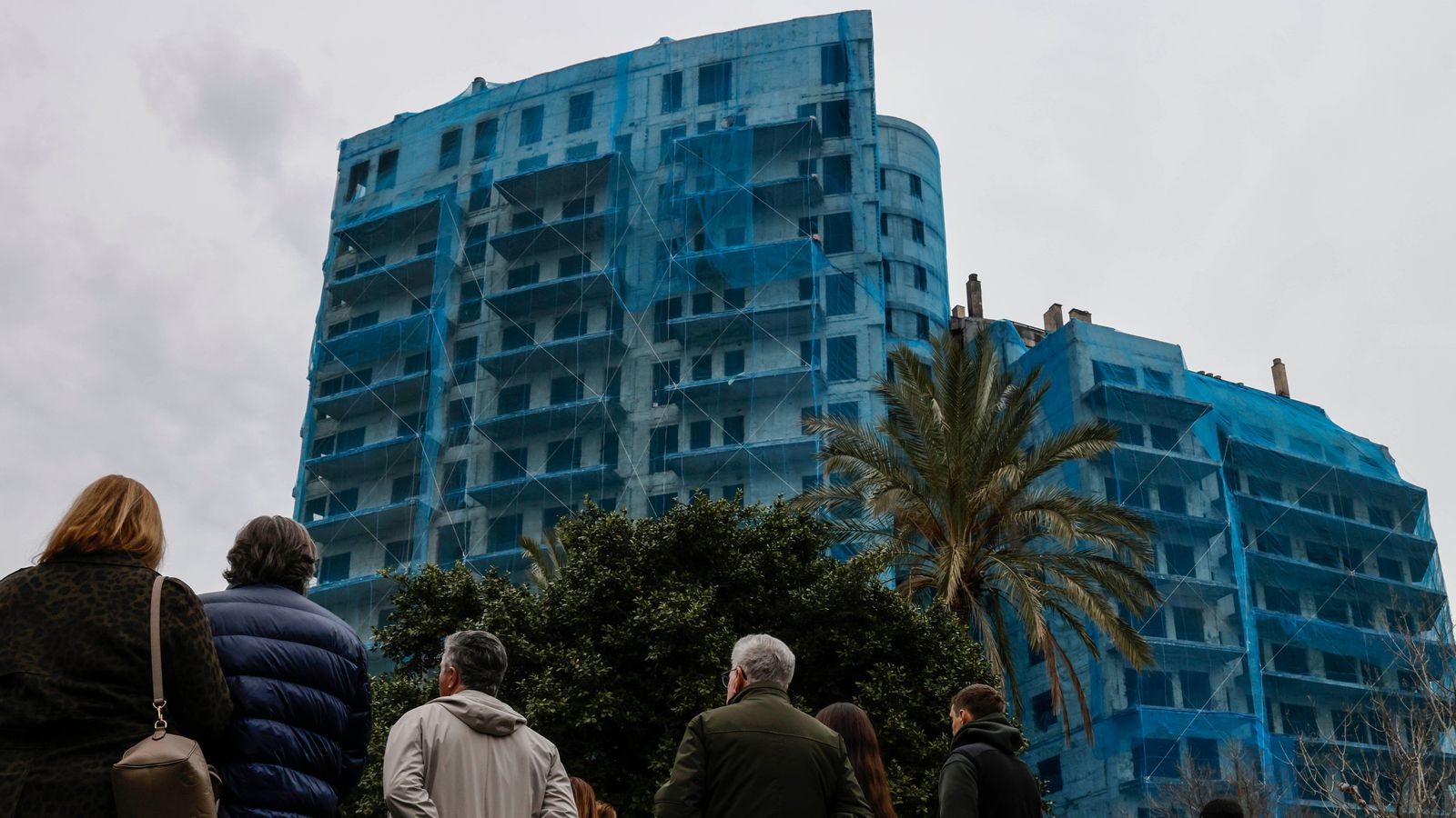 Diverses persones contemplen l'edifici de Campanar en l'acte del primer aniversari de l'incendi