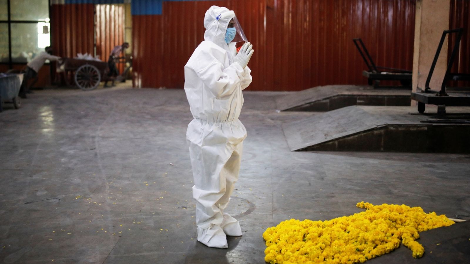 Un veí de Nova Delhi dóna l'últim adéu a un familiar vestit amb un EPI