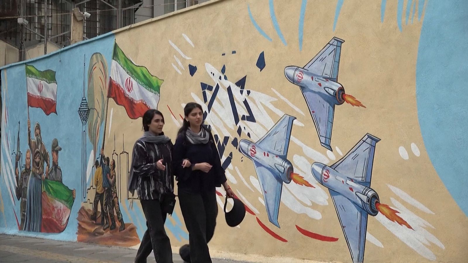 Dos joves passegen davant d'un mural