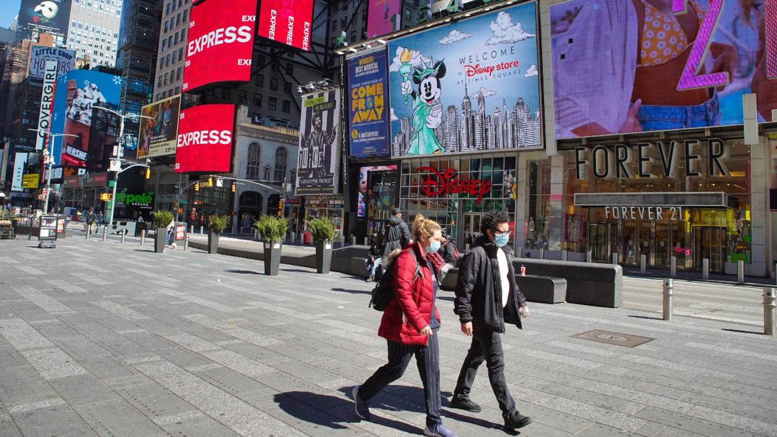 Uns vianants passegen per Times Square, buida per la pandèmia