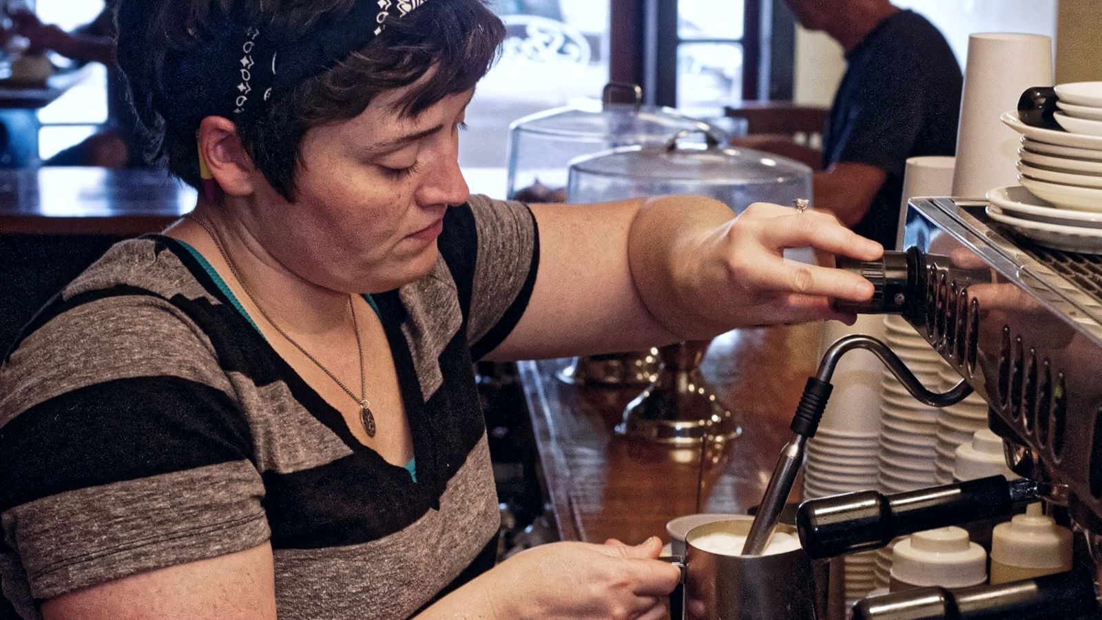 Una cambrera prepara una tassa de café