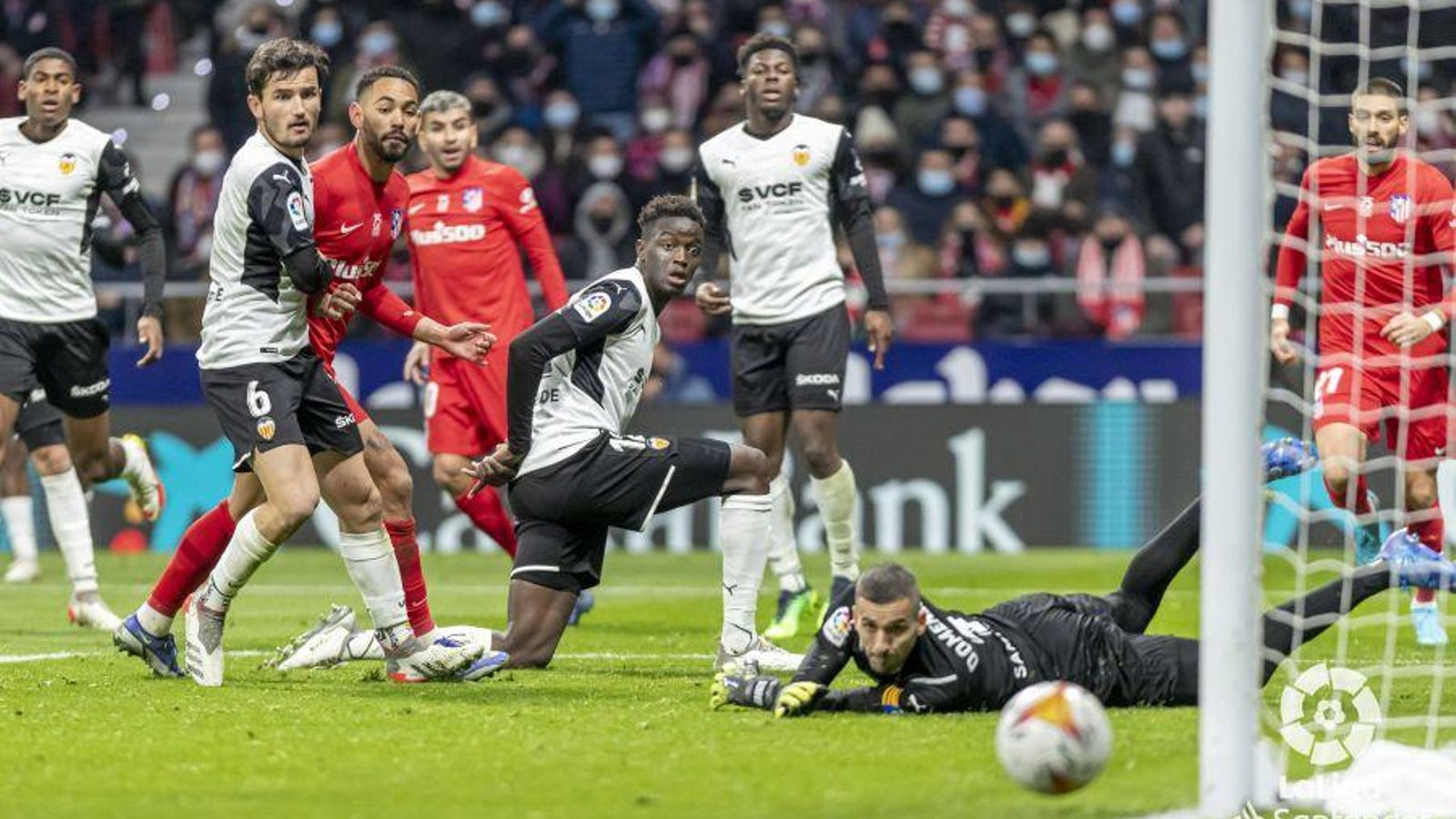 Els jugadors d'Atlètic i València miren com una pilota passa fregant la porteria