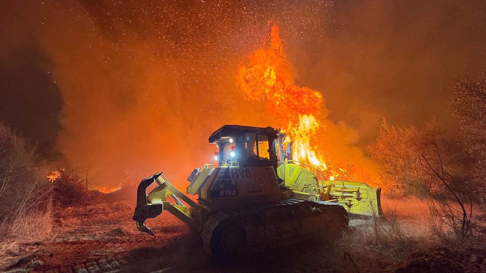 Un tractor tracta de posar barreres a Aguasmestas, al municipi de Quiroga, a l'incendi que devora la massa forestal