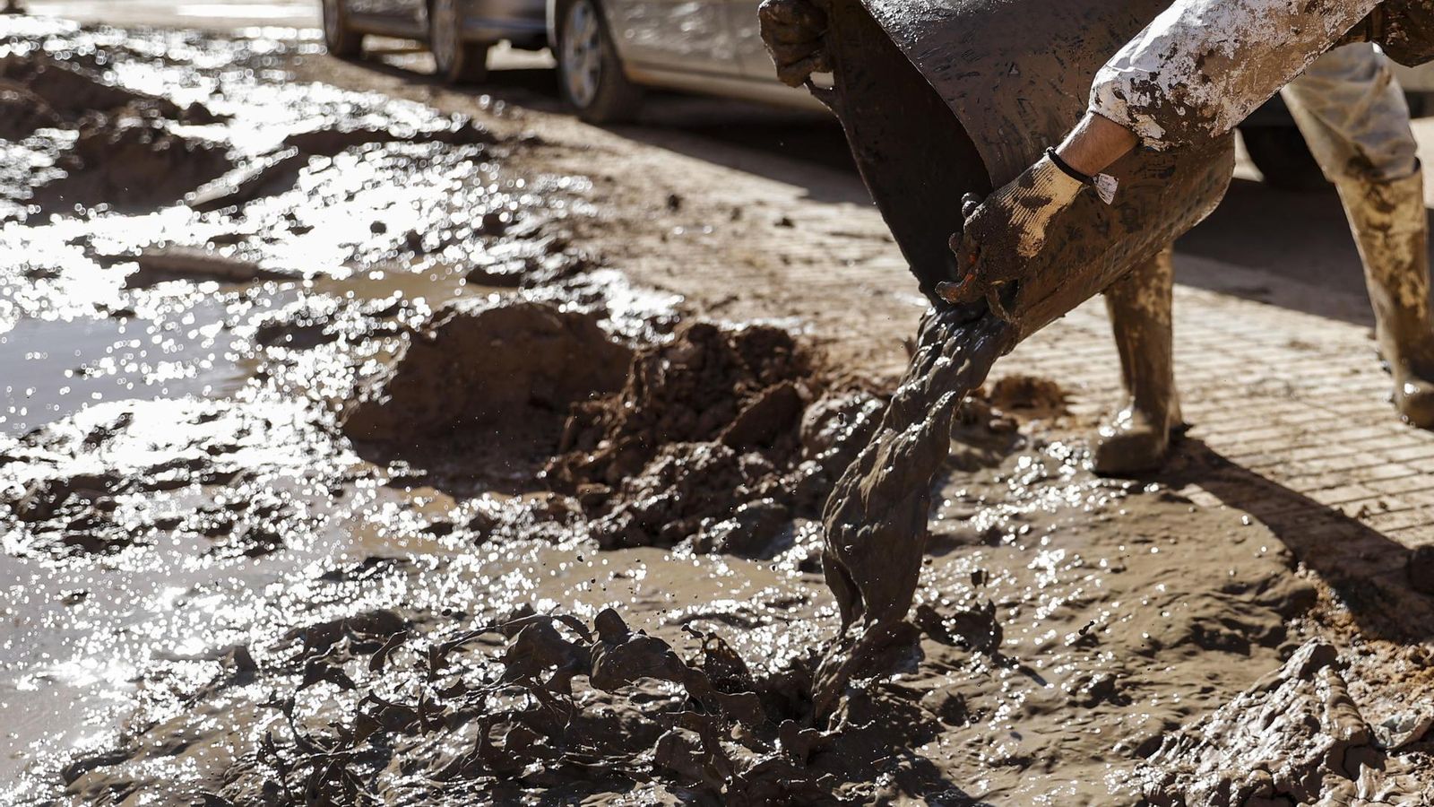 Dos voluntaris buiden un cabàs de fang de la Dana