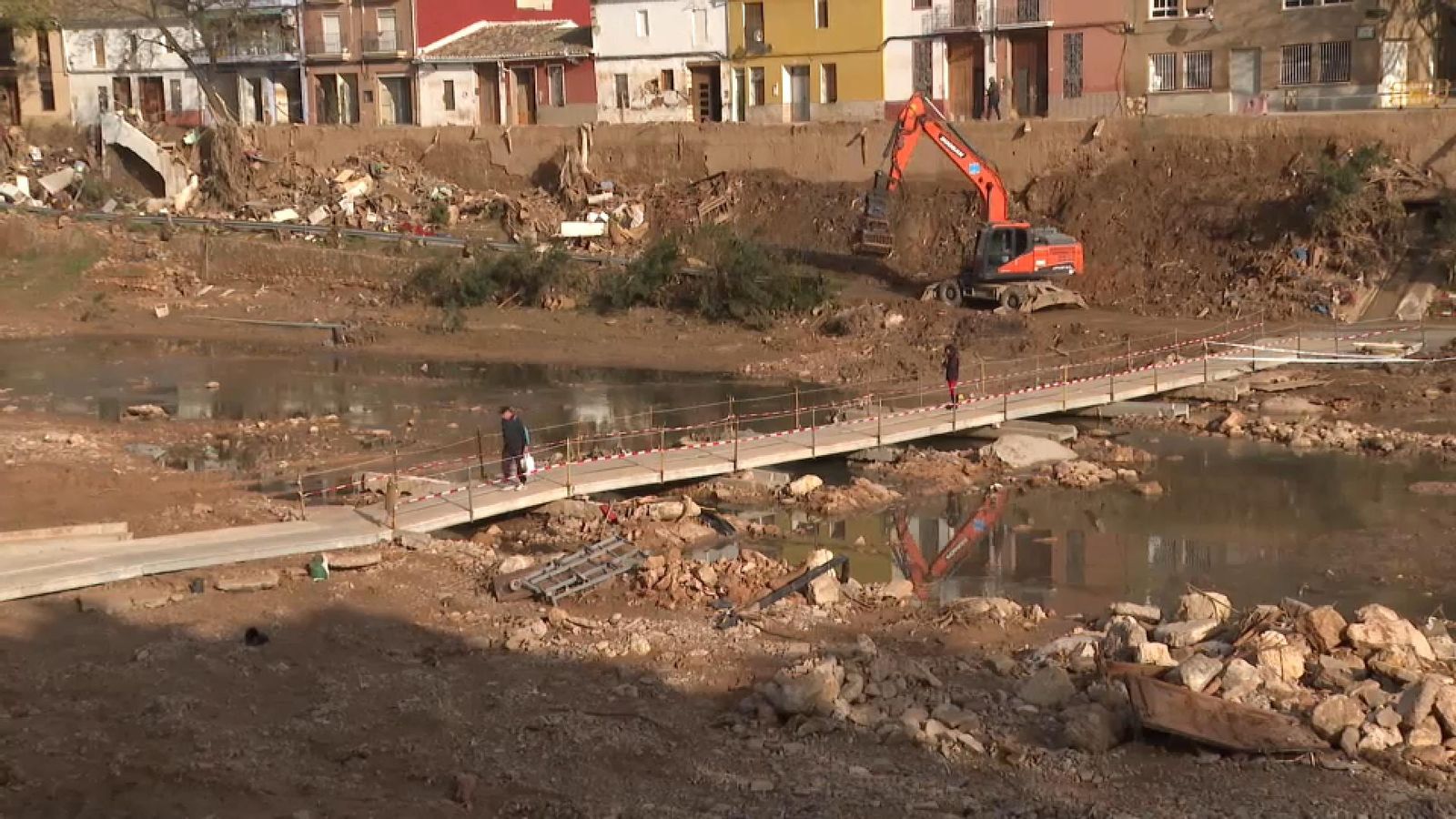 Veïns del barri de Vistabella de Picanya salven el barranc amb un pont casolà que fabricaren amb taulons, portes de casa i palés sobre les pedres i que ha reforçat una empresa privada.