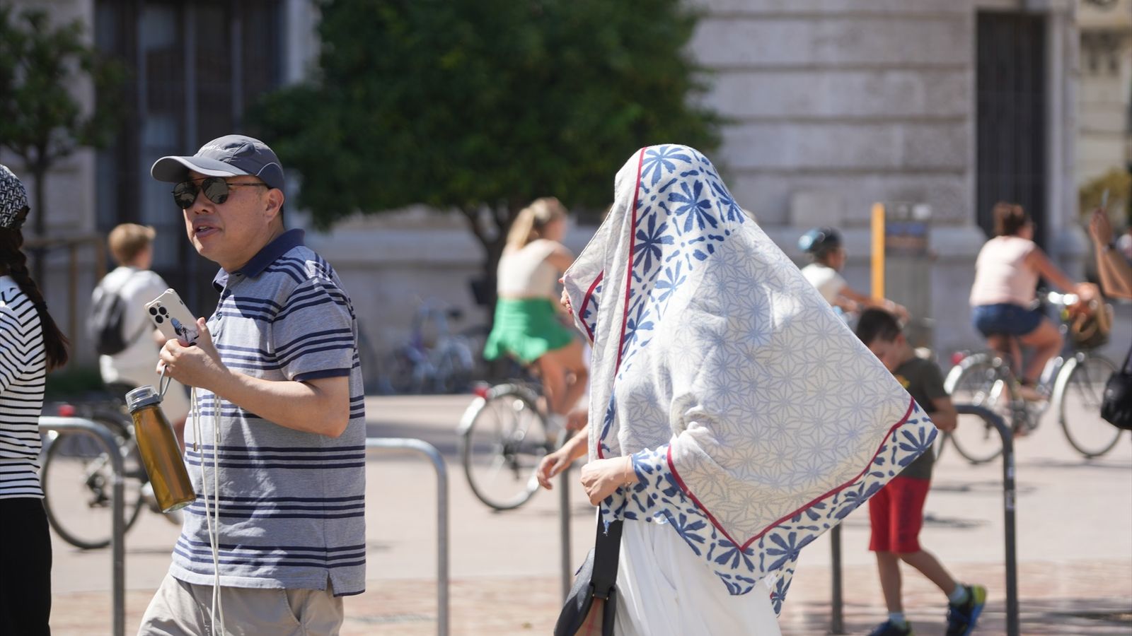 Dues persones caminen per València tapades per a protegir-se de la calor