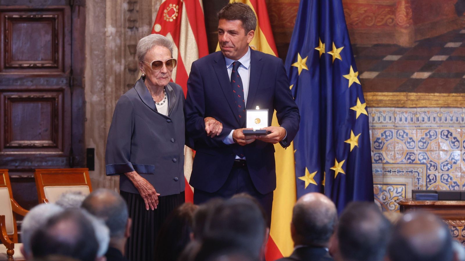 Amparo Cabanes, agafada del braç del president Mazón, en recollir l'Alta Distinció de la Generalitat