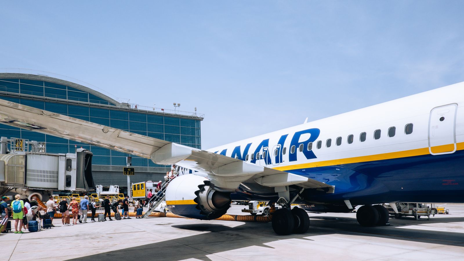 Diverses persones fan cua per a pujar-se a un avió de la flota de Ryanair a l'aeroport d'Alacant