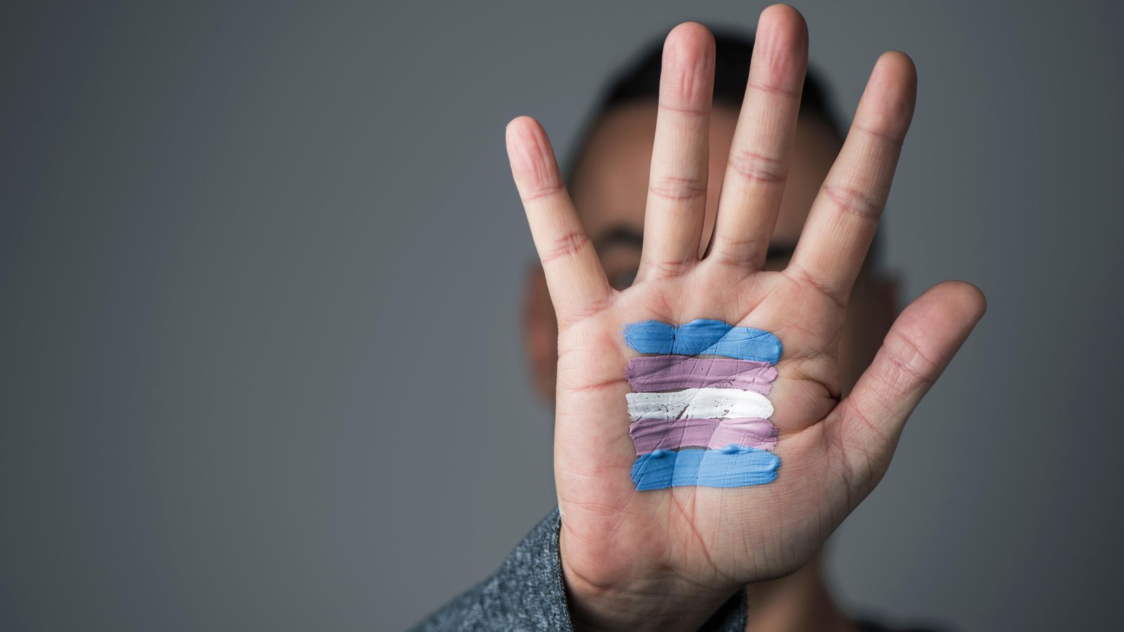 Una persona amb una bandera trans pintada a la mà