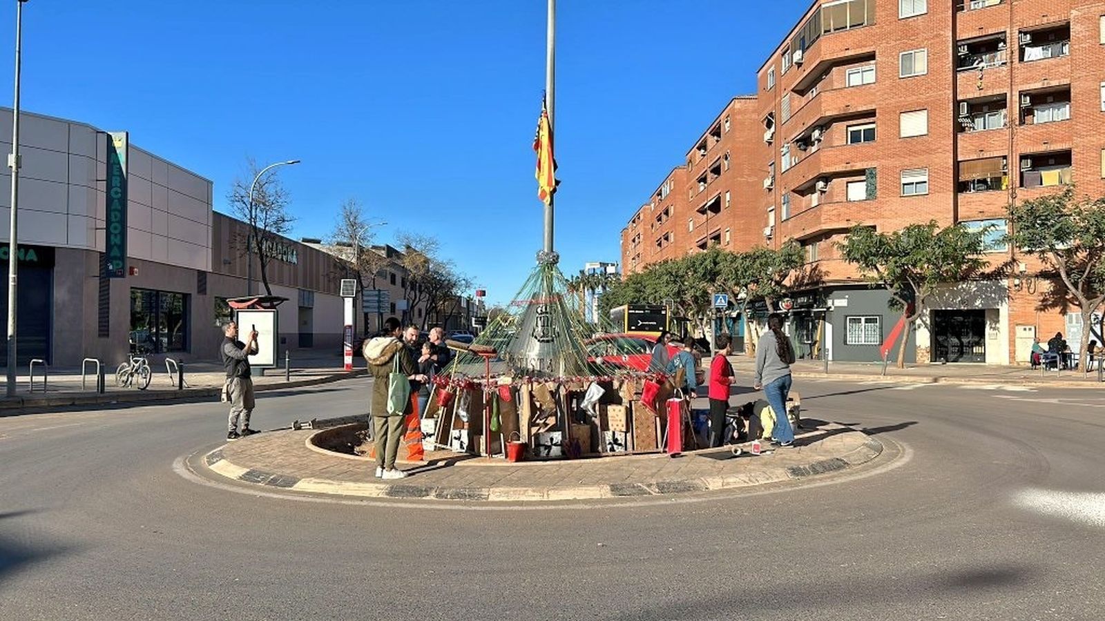 Un grup de veïns i veïnes amb l'arbre improvisat de Nadal
