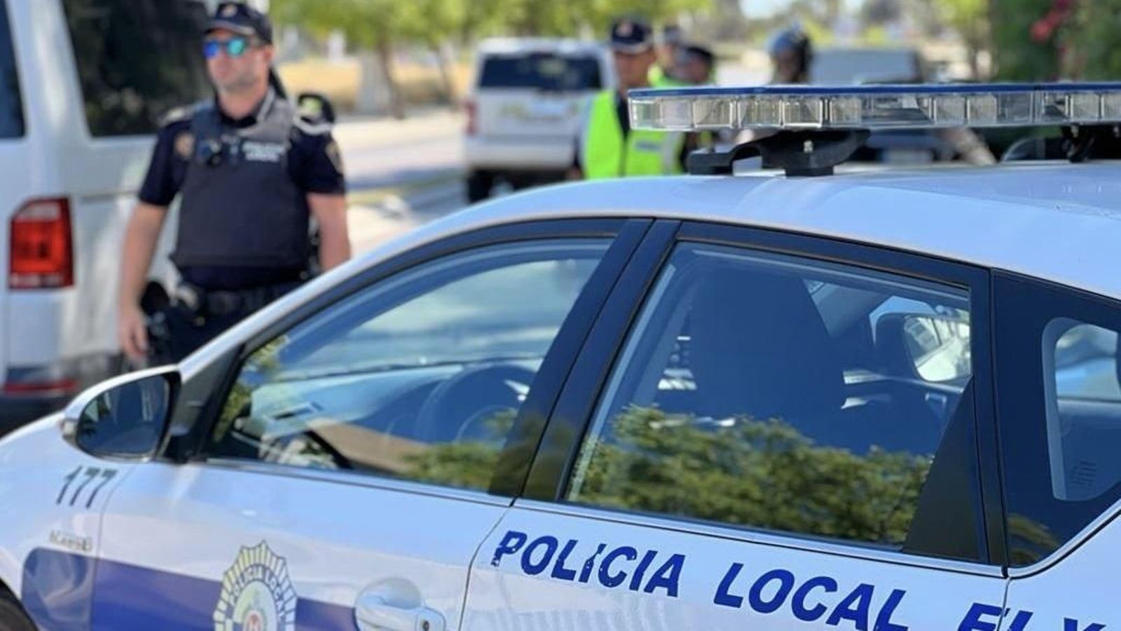 Un agent de la Policia Local d'Elx, junt amb un vehicle (arxiu)