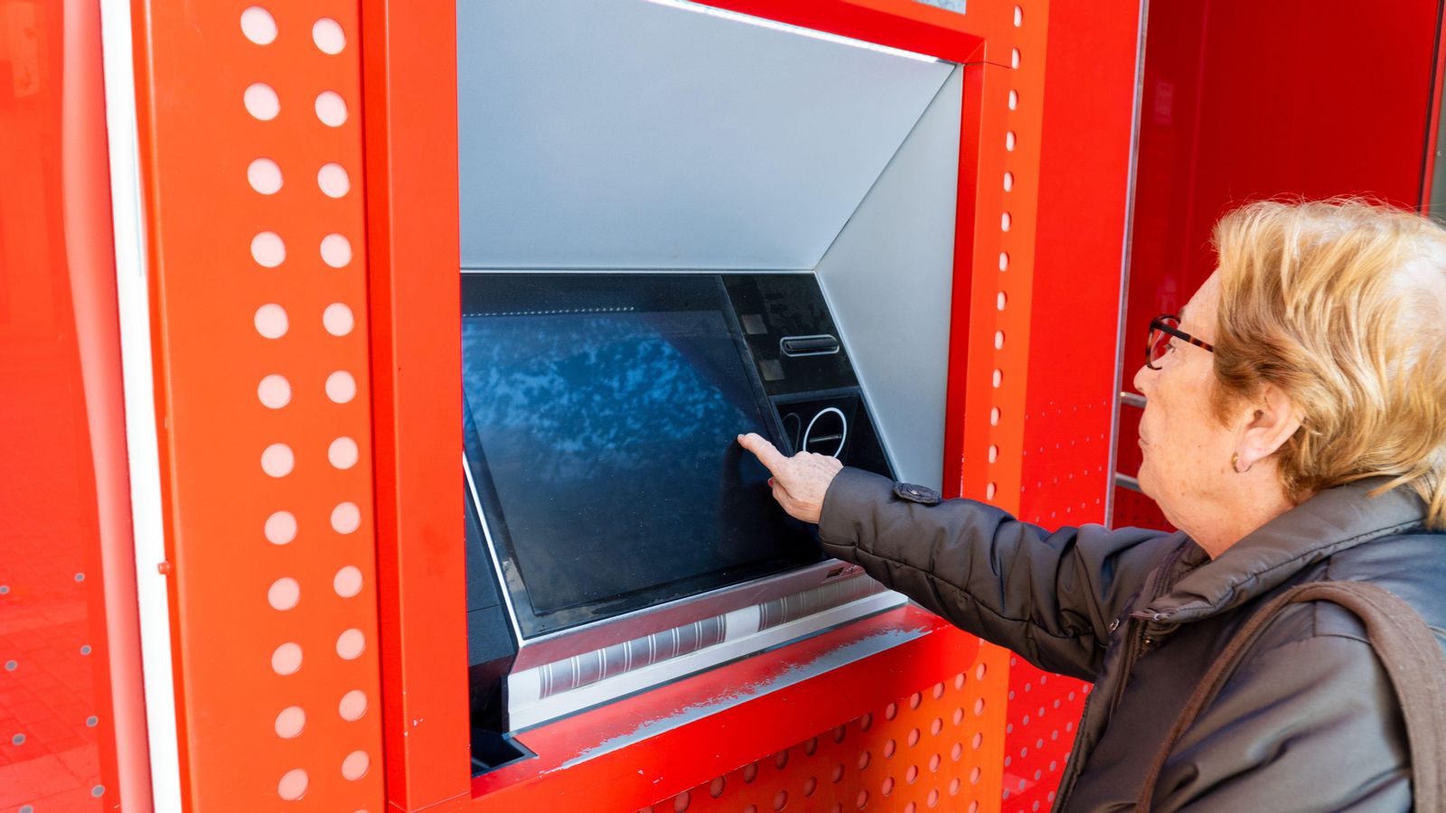 Una dona major trau diners del caixer