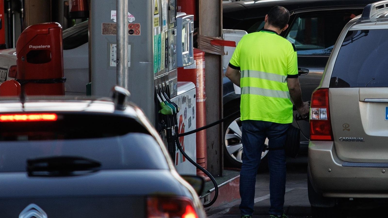 Un operari ompli un vehicle en una gasolinera