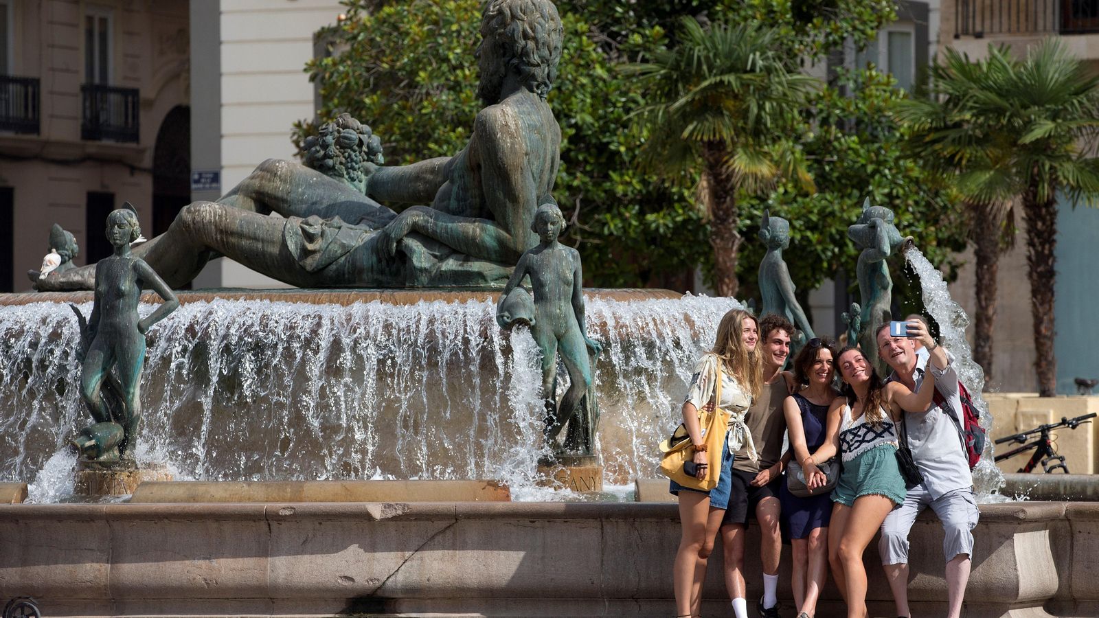 Un grup de turistes es fotografia a la plaça de la Reina de València