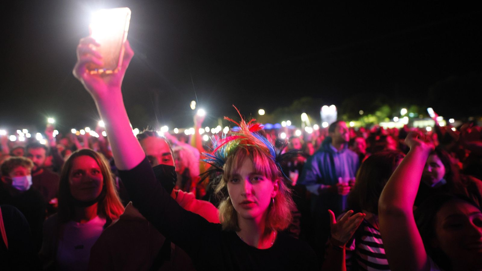 Una xica il·lumina amb el seu mòbil l'escenari durant un concert al festival Sansan de Benicàssim 2021