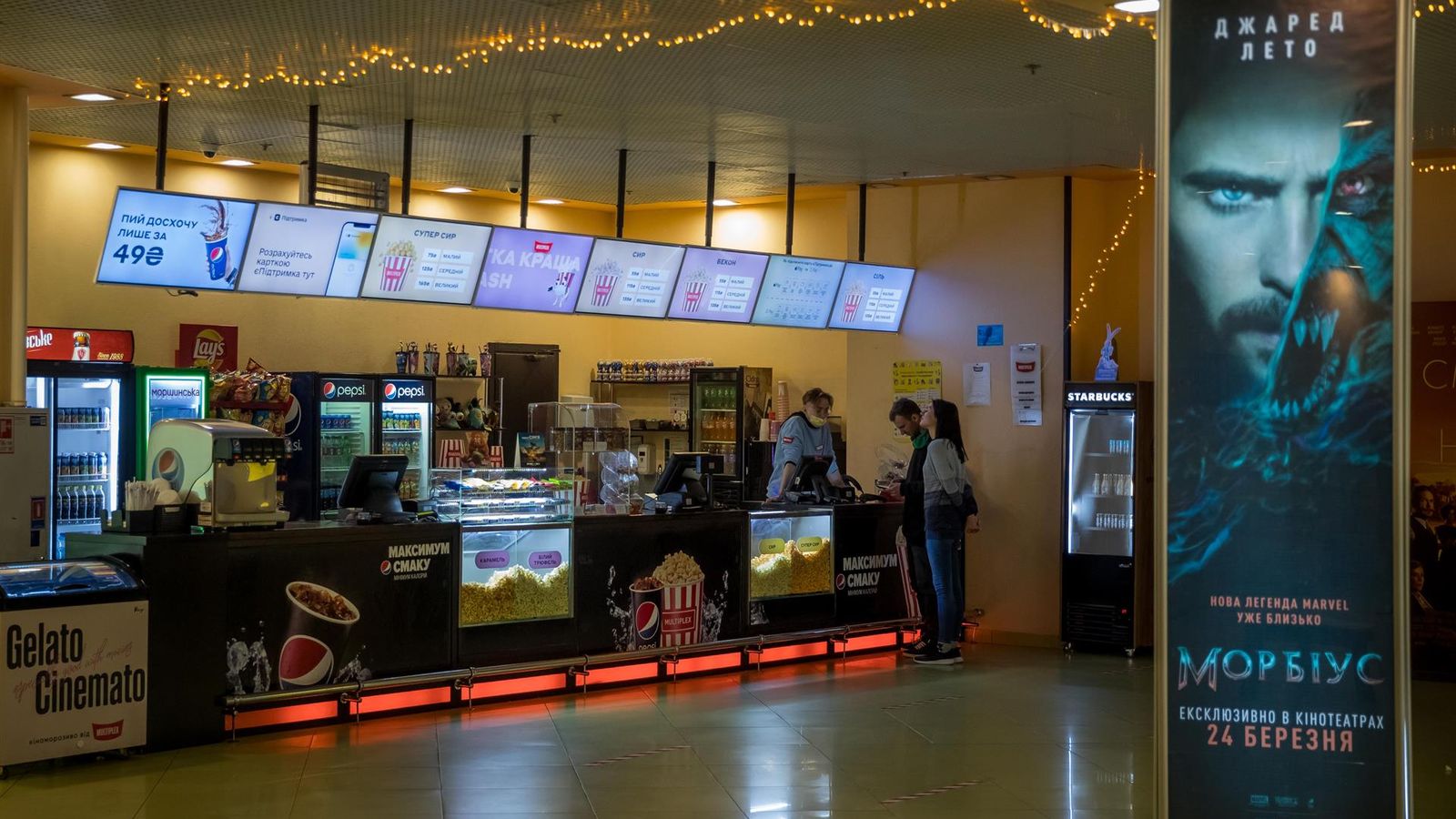 Dues persones compren roses a l'entrada d'un cinema a Kíiv