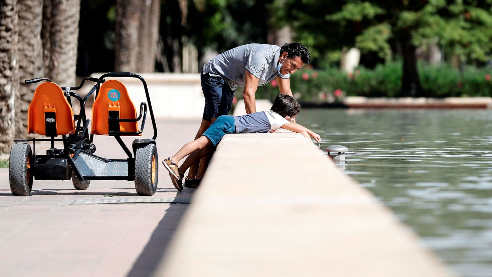 Un pare i un fill es refresquen en una font de la ciutat de València