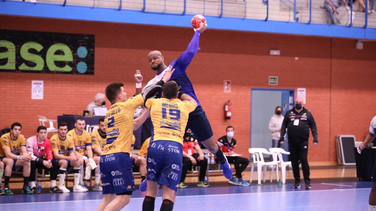 Un jugador del Benidorm llança a porteria davant la defensa de dos jugadors rivals