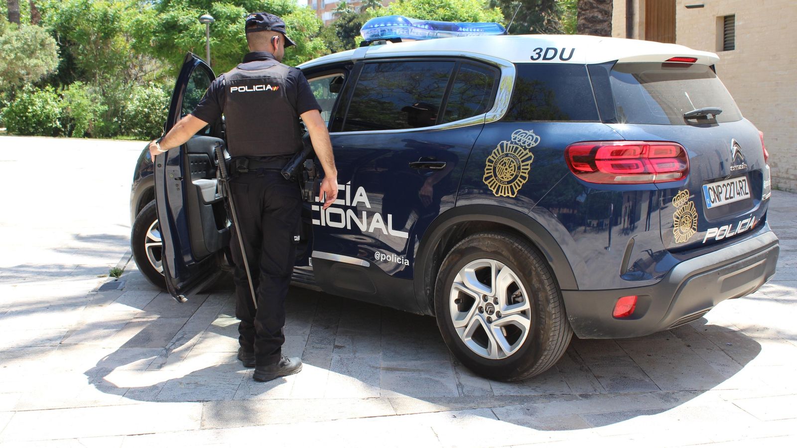 Un vehicle i un agent de la Policia Nacional