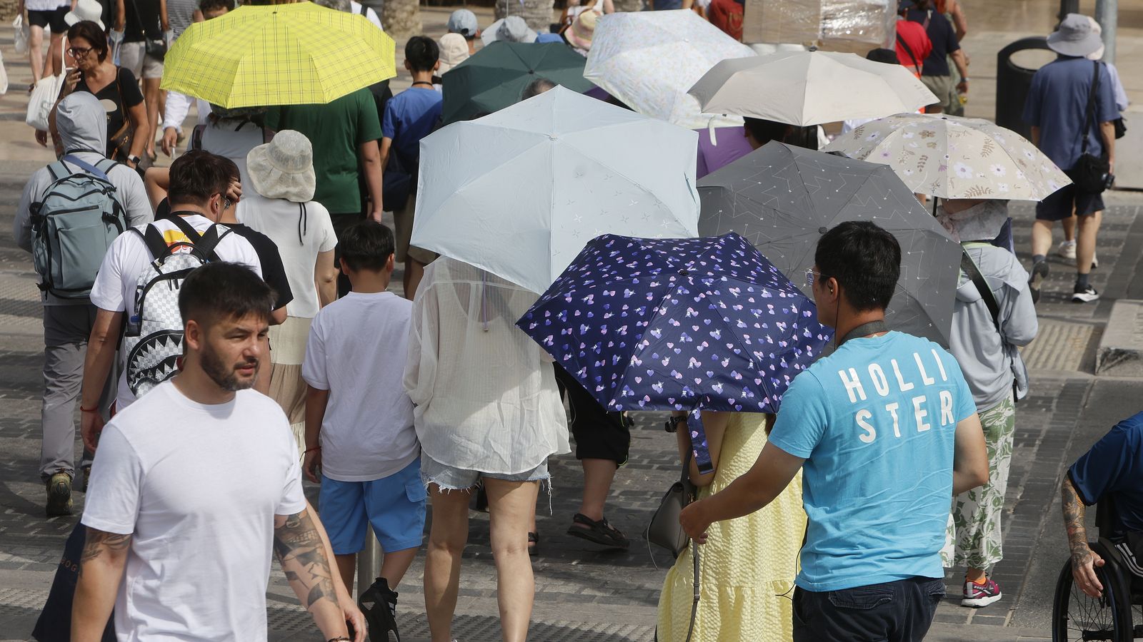 Turistes amb paraigües per refugiar-se de la calor