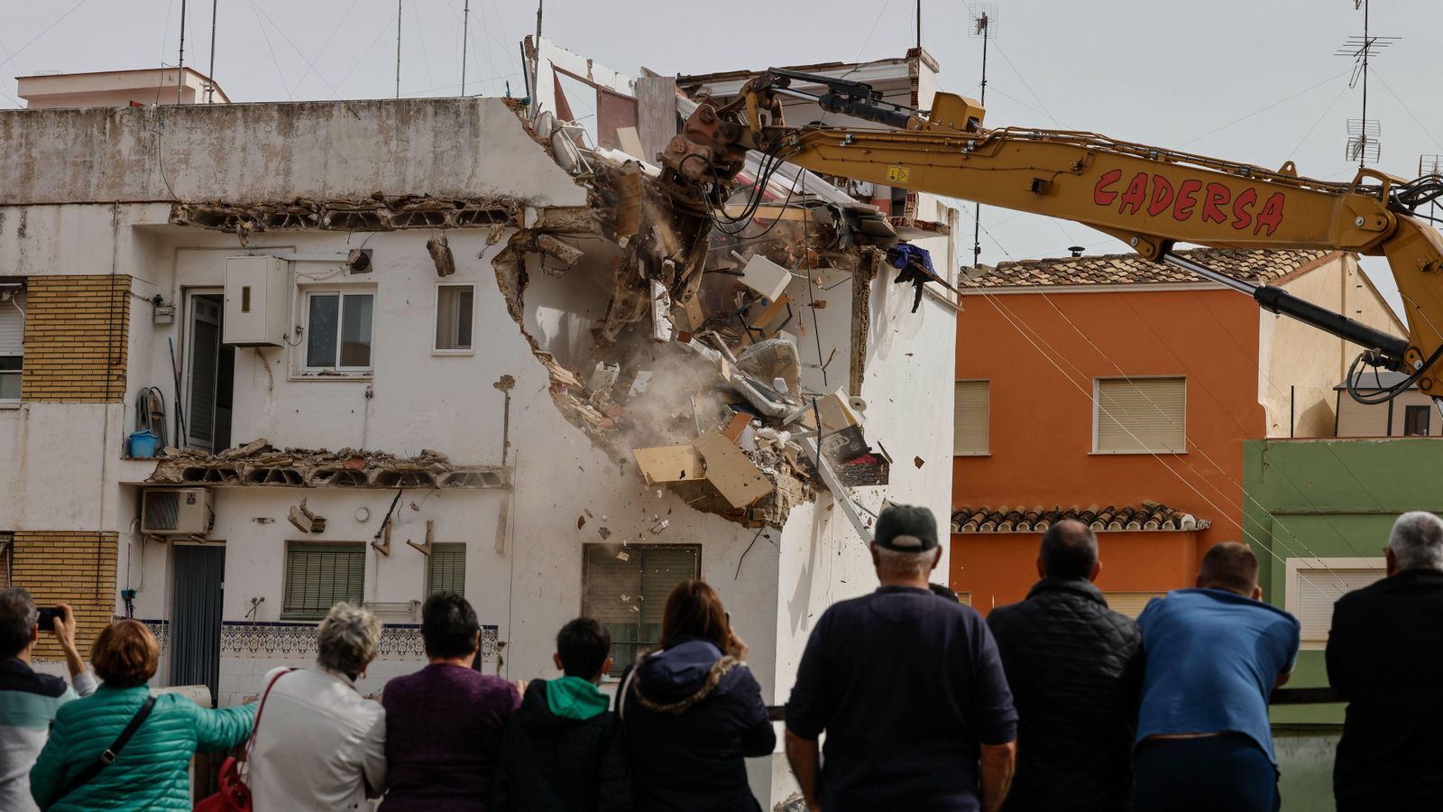 Un grup de veïns observa com las màquines enderroquen diverses vivendes que la dana va llançar a perdre