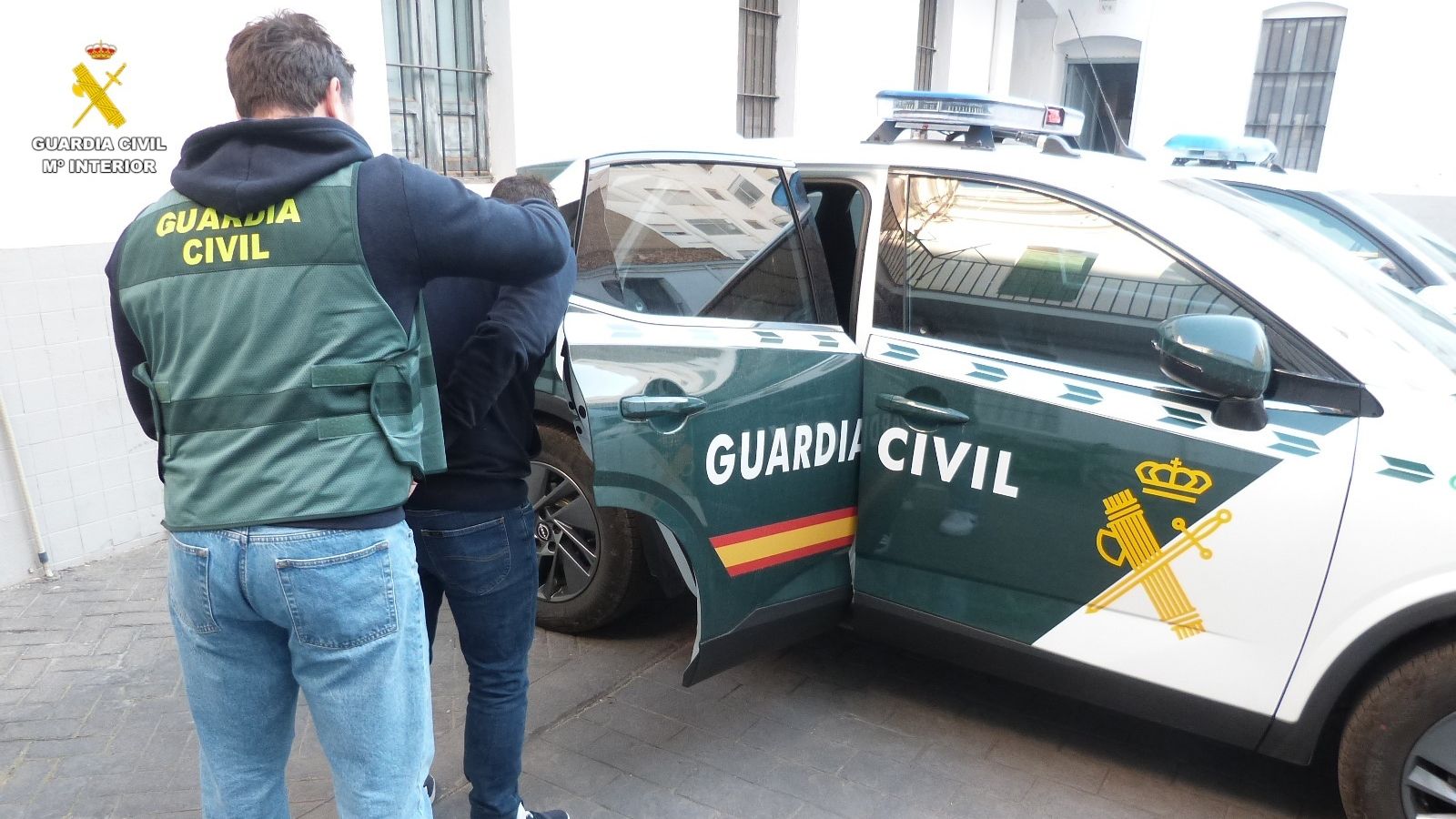 Un agent custodia el detingut en un vehicle policial