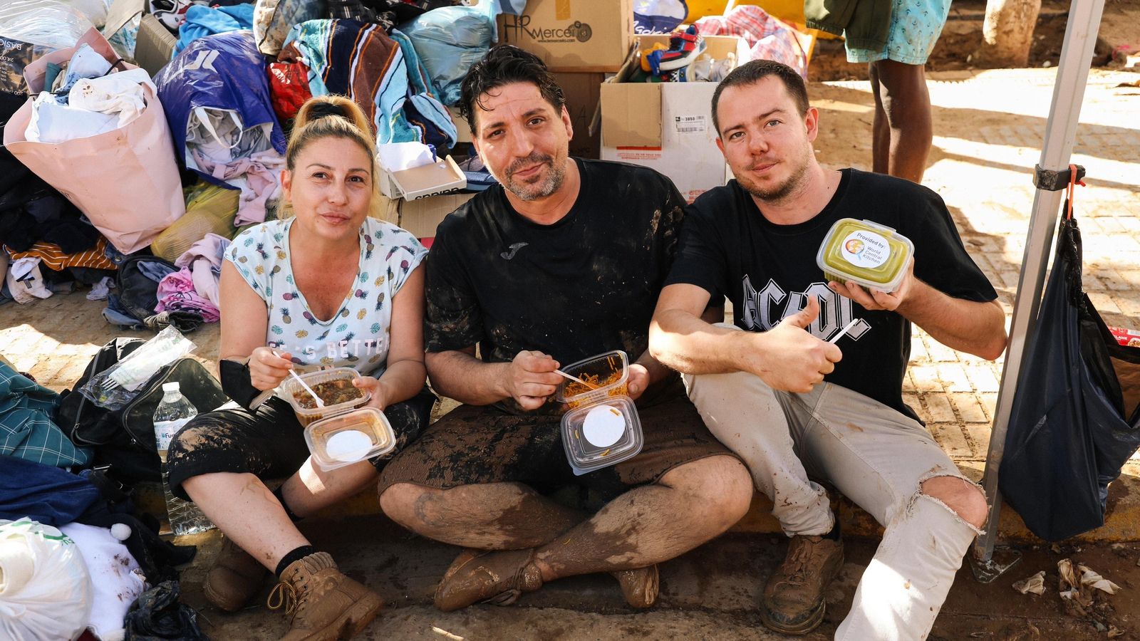 Voluntaris tacats de fang paren per a menjar envoltats de roba donada