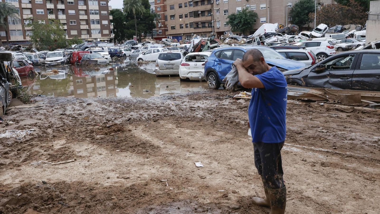 Un home al costat de diversos cotxes, arrossegats per l'aigua després del pas de la DANA, a Paiporta (Horta Sud), este divendres