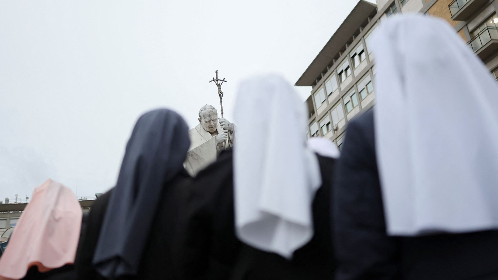Monges enfront de l'estàtua del papa a l'Hospital Gemelli de Roma