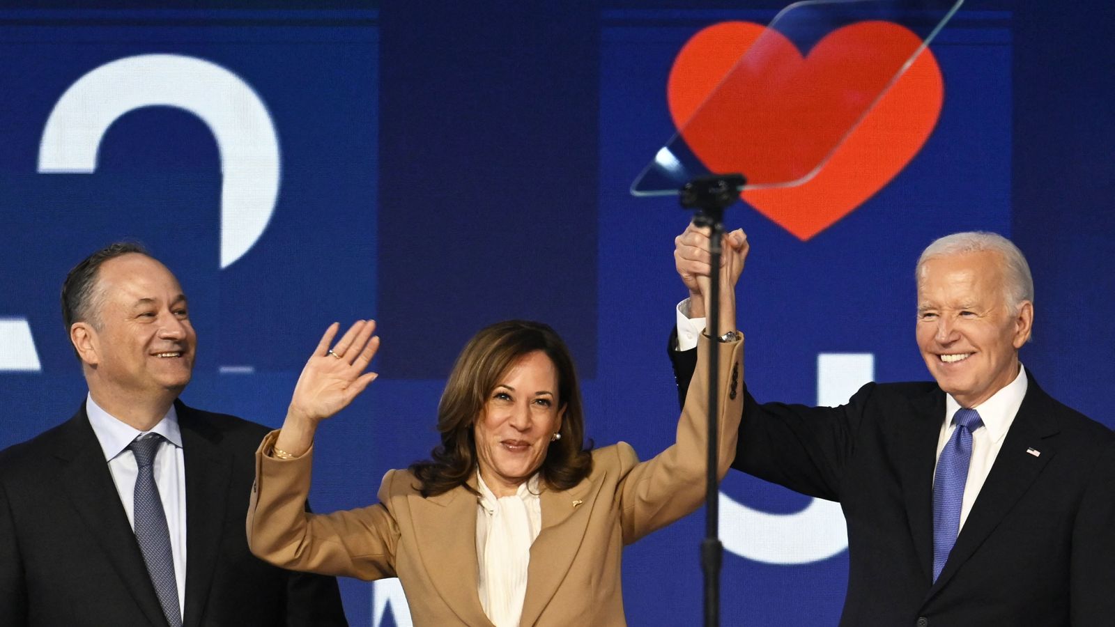 Biden i Kamala Harris (dreta i centre) s'agafen les mans a l'escenari de l'United Center, acompanyats per l'home, Doug Emhoff (esquerra)
