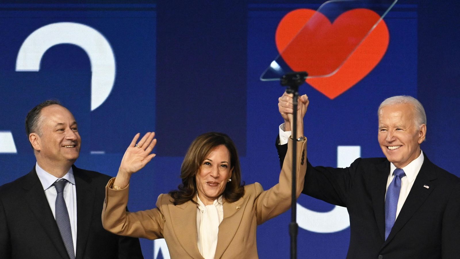 Biden i Kamala Harris (dreta i centre) s'agafen les mans a l'escenari del United Center, acompanyats per l'home d'ella, Doug Emhoff (esquerra) Biden i Kamala Harris (dreta i centre) s'agafen les mans a l'escenari de l'United Center, acompanyats per l'home, Doug Emhoff (esquerra)