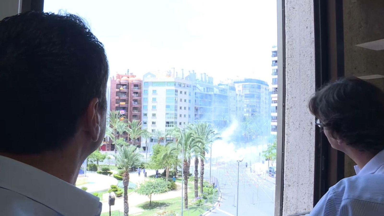 Dos espectadors segueixen la mascletà des d'un dels balcons amb vistes a la plaça dels Estels llogats