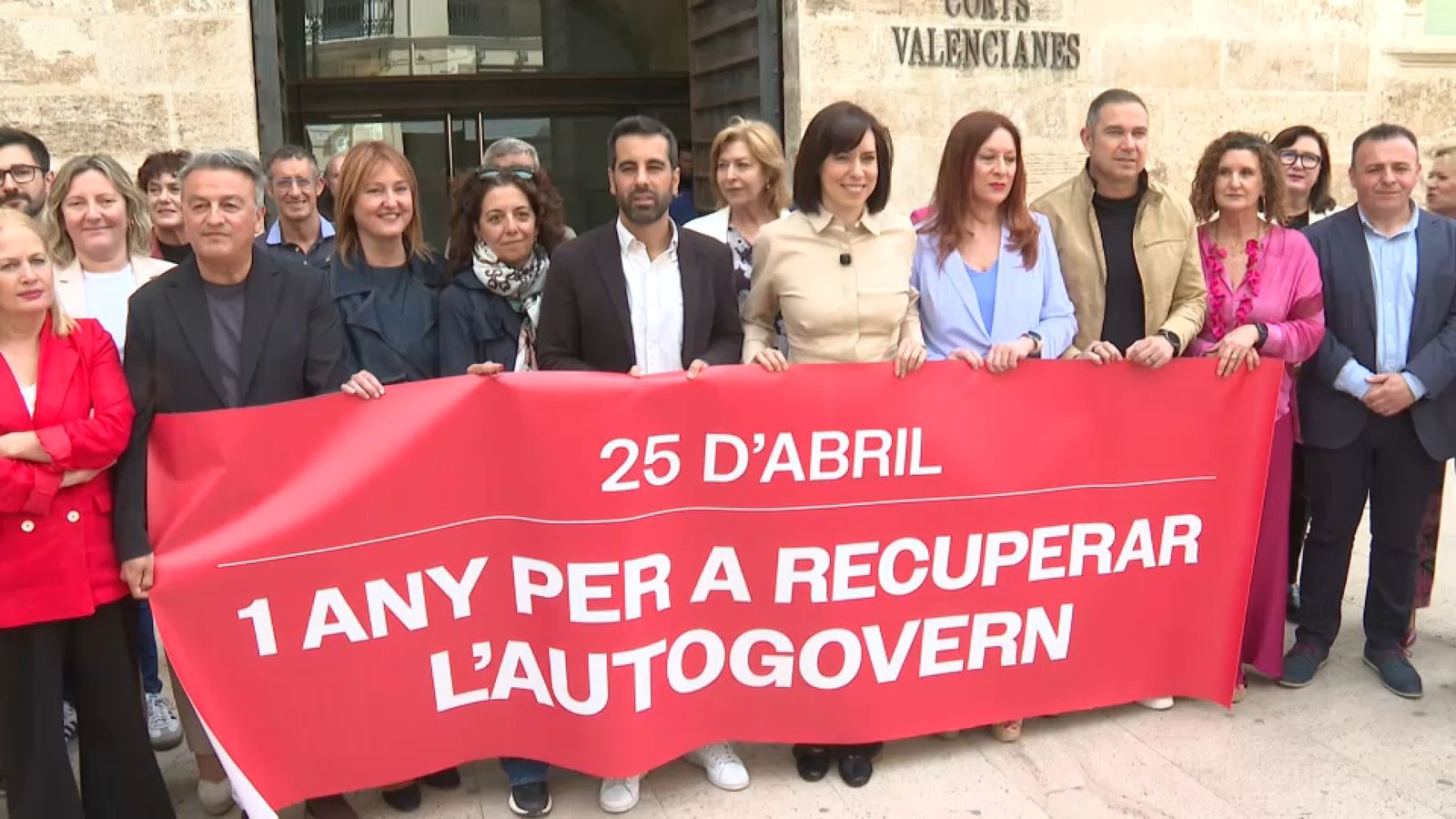 Els diputats del PSPV, amb la secretària general dels socialistes Diana Morant en el centre, posen davant de les Corts amb la pancarta commemorativa