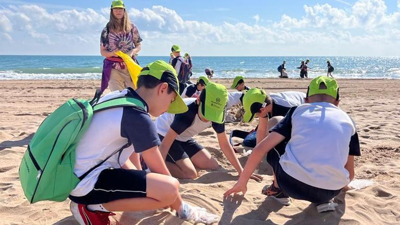 Un grup d'estudiants de primària arreplega plàstics de la platja a Tavernes de la Valldigna