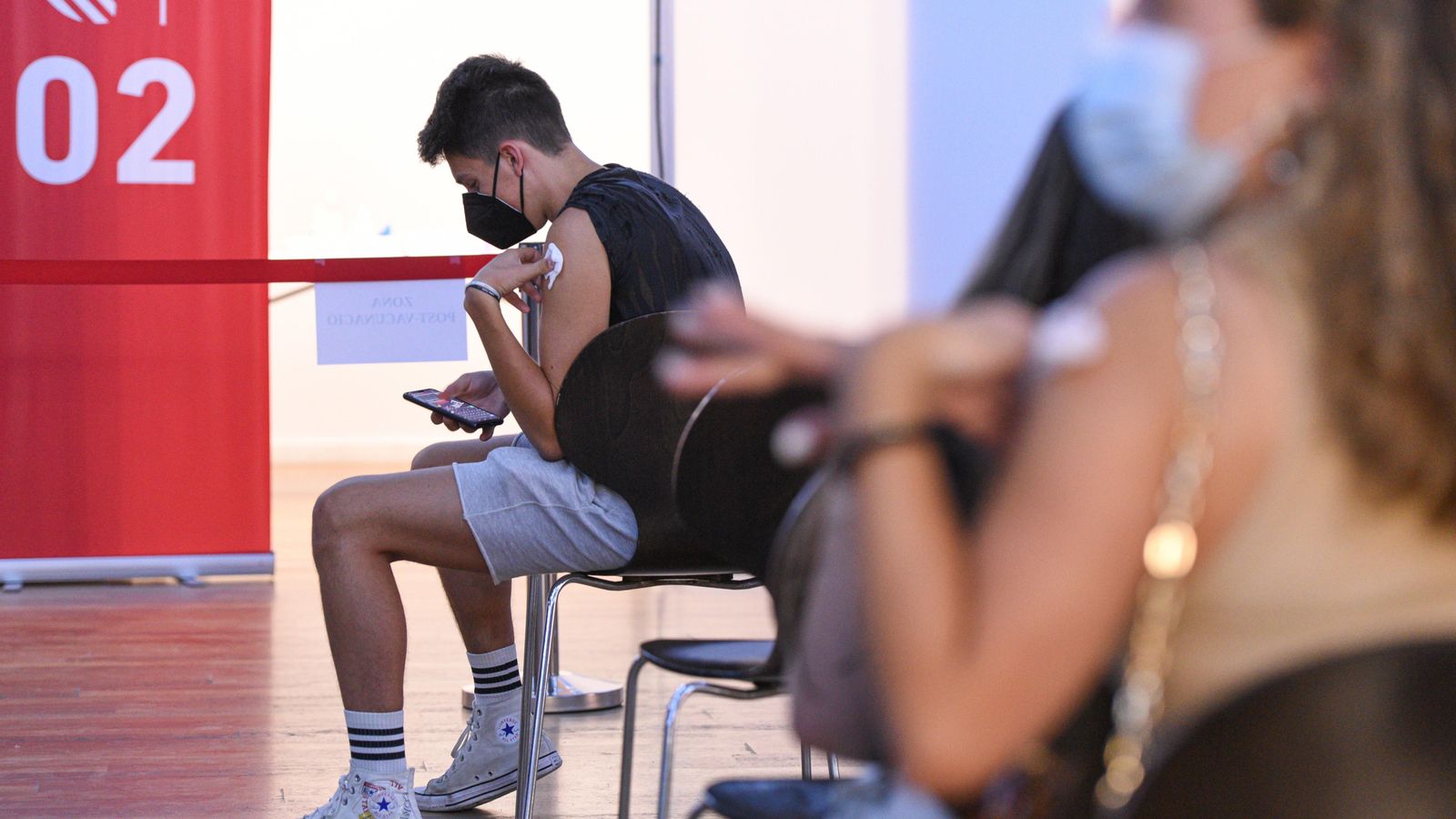 Un adolescent espera en una sala del punt de vacunació de Xátiva, situat en la Llar dels Jubilats