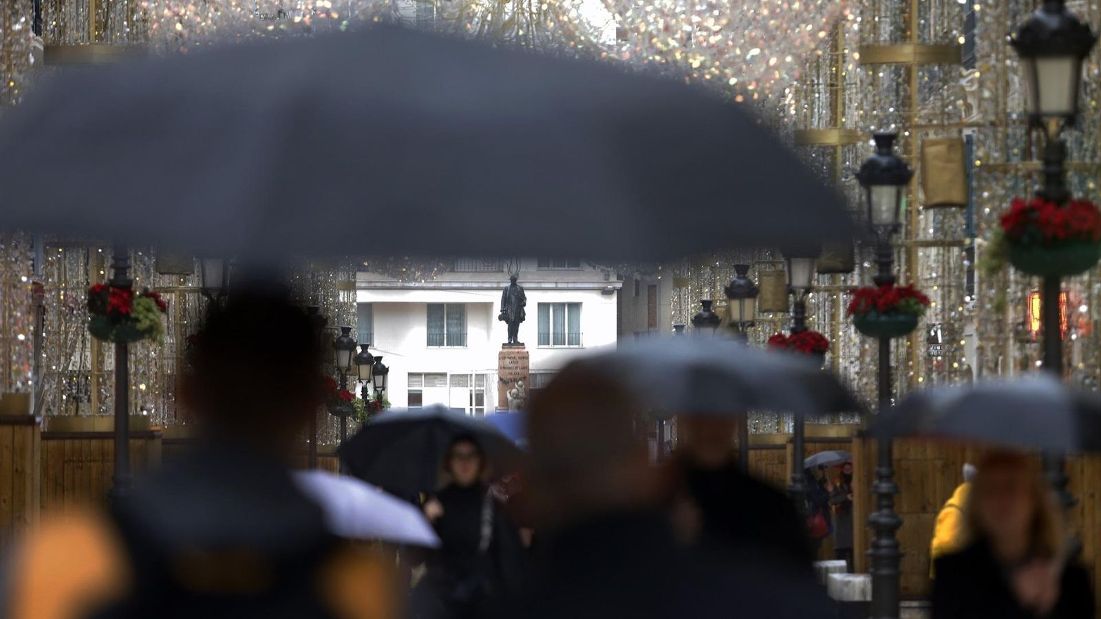 Diverses persones es protegeixen de la pluja, en una imatge d'arxiu