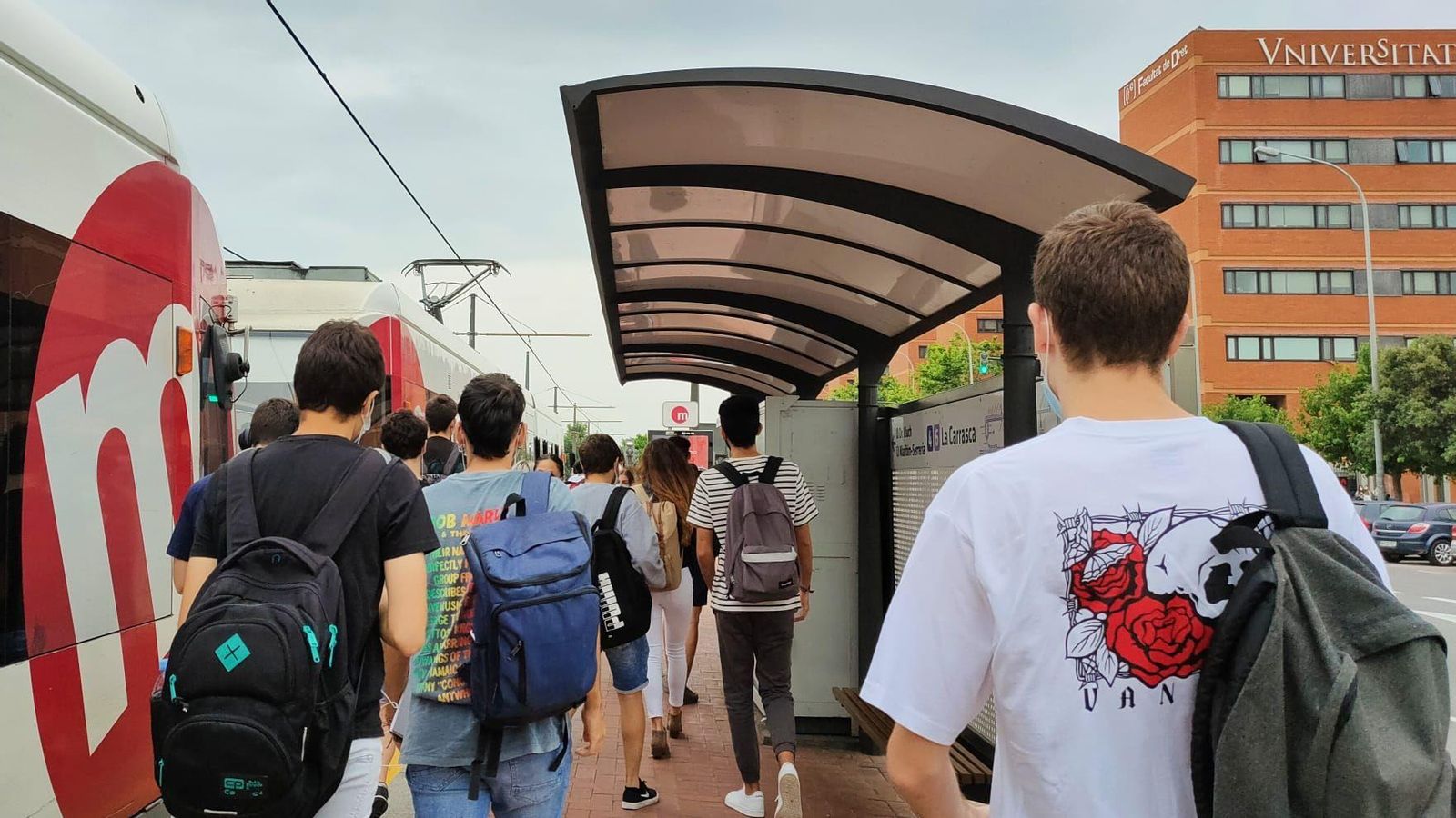 Un grup de joves caminen per l'andana en una parada del tramvia de la ciutat de València