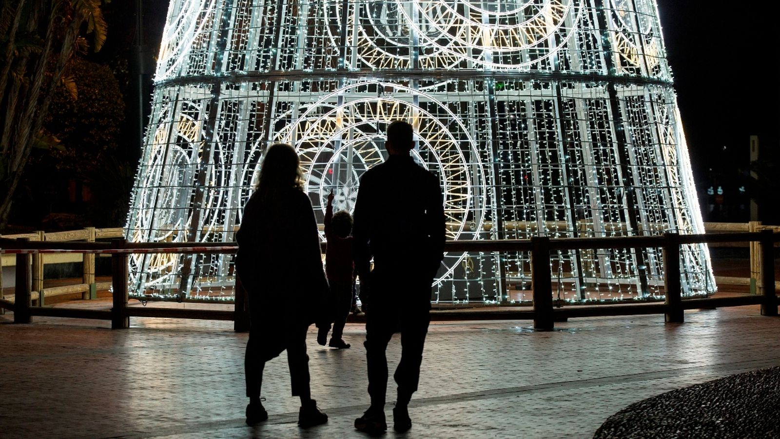 Una parella i el seu fill observen un arbre de Nadal d’un carrer de Málaga