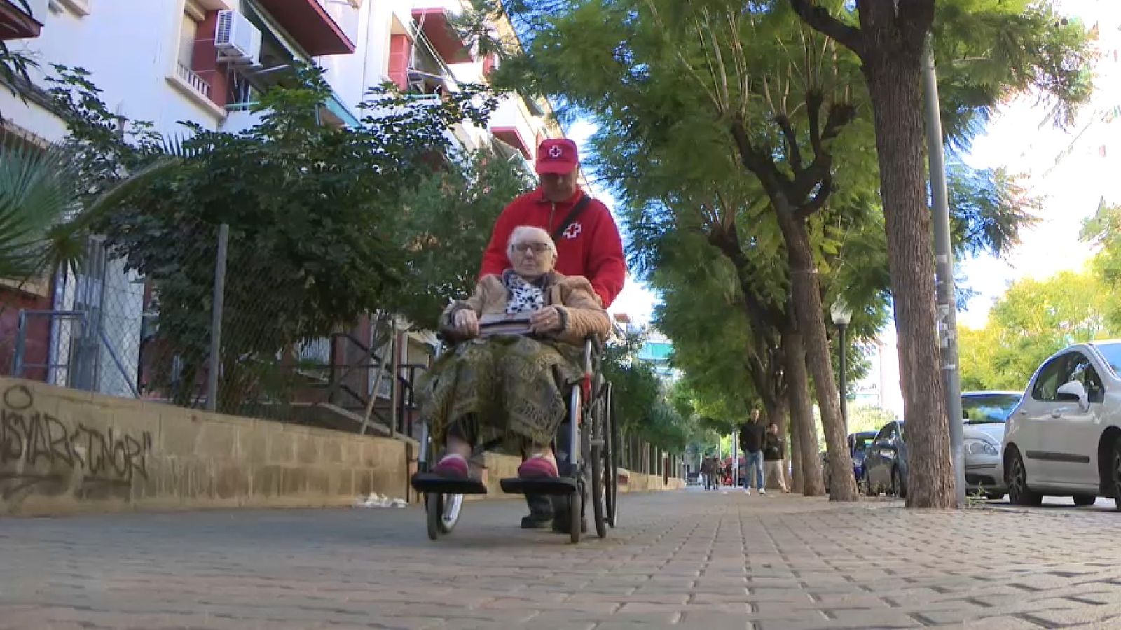 Anselma, de 93 anys, i Paco, el voluntari de la Creu Roja que la visita, en el primer passeig d'Anselma pel barri després de cinc mesos