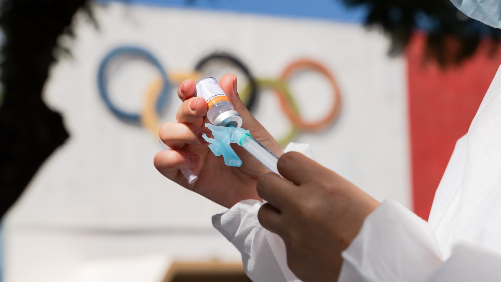 Una infermera prepara una dosi de la vacuna davant del logo dels Jocs Olímpics